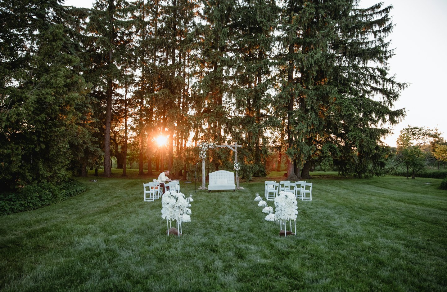 Wedding chairs and flower arrangements set up on a lawn.