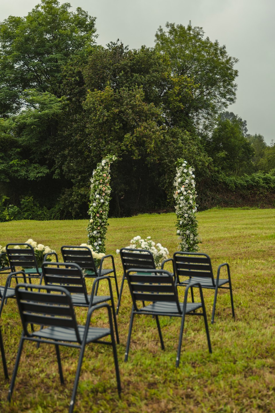 Two floral arches on a green lawn for an outdoor ceremony.