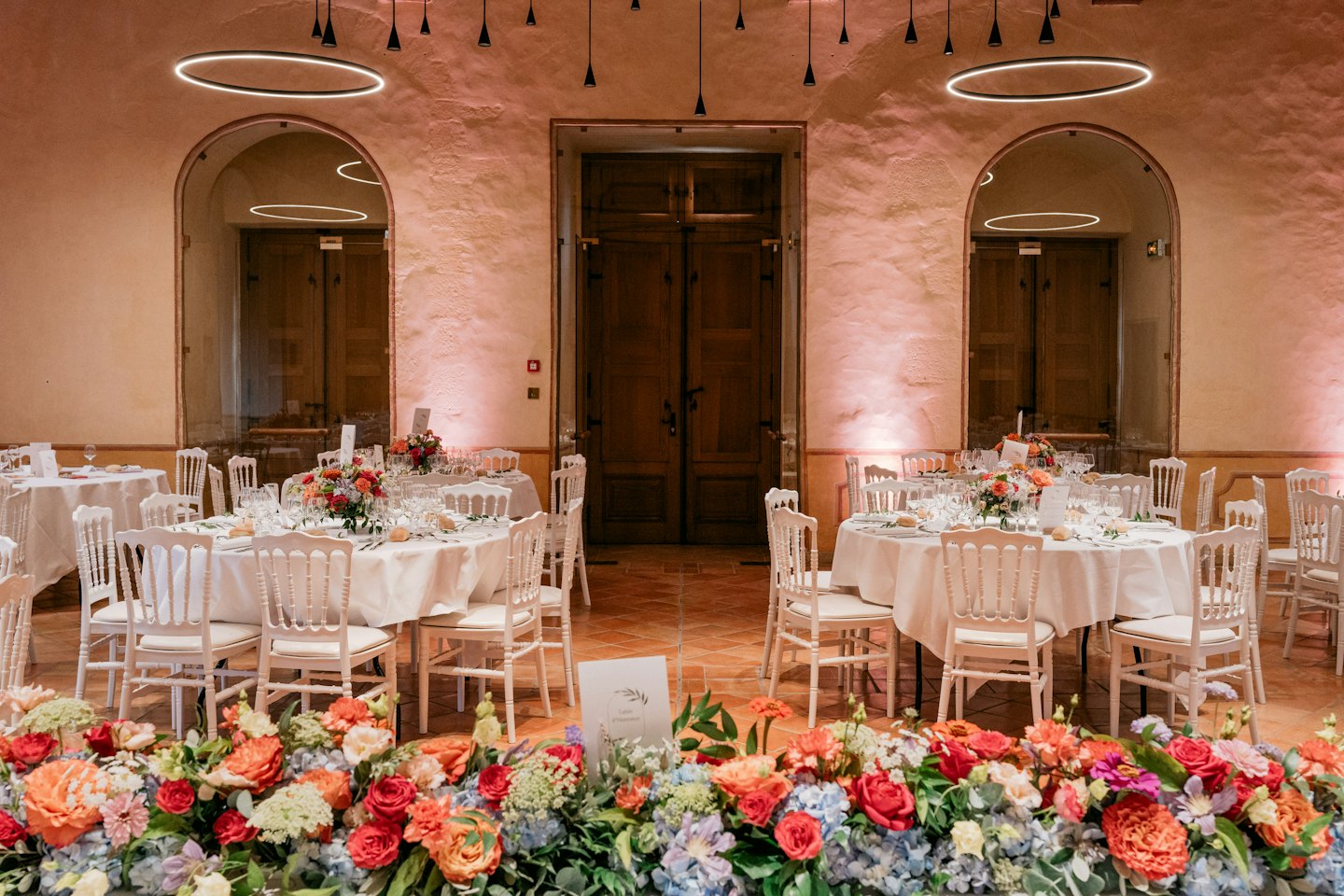 Elegantly set event hall tables with floral centerpieces.