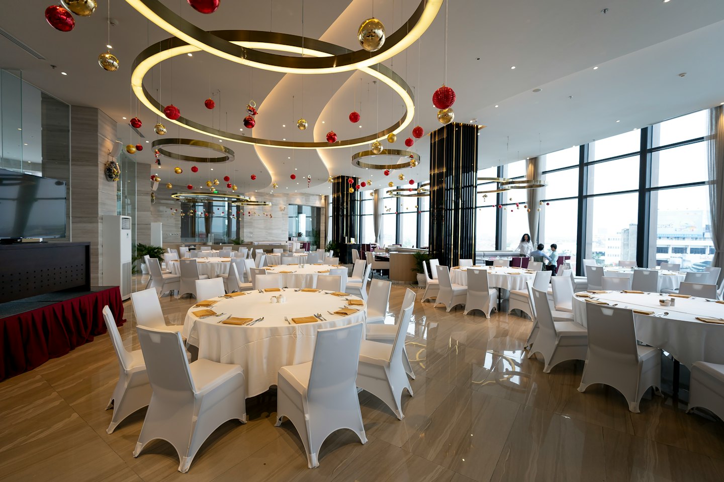Modern banquet hall decorated for an event with round tables.